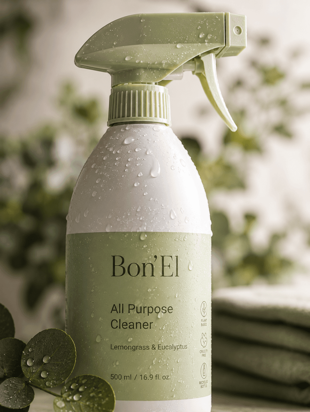 A Bon'El all purpose cleaner bottle beaded with water, eucalyptus leaves behind it